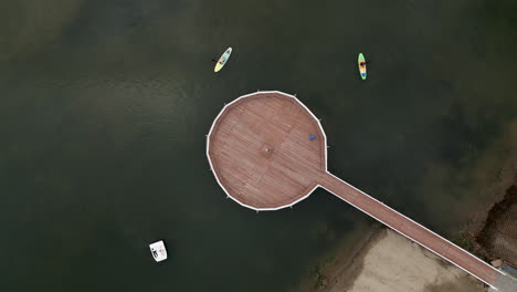 circular wooden pier on a lake with paddleboards