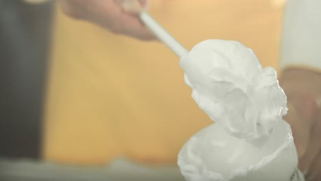 chef puts beautiful fluffy white vegan egg white cream out of a cup and holds it on a spoon