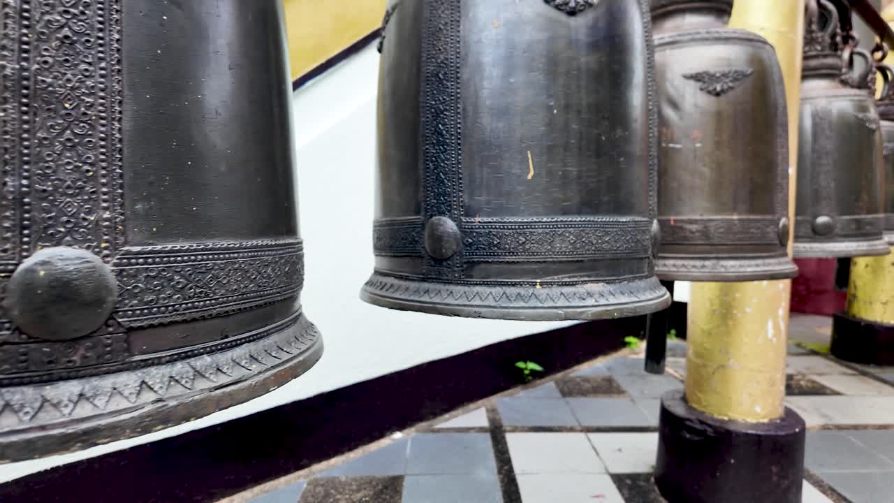 Bronze temple bells with intricate patterns hang at Doi Suthep Temple, Chiang Mai, evoking sacred tradition and spiritual atmosphere
