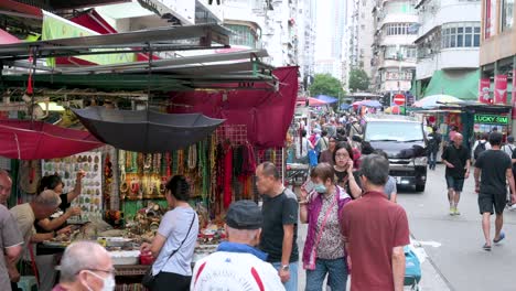 people window shopping at a market stall selling jade stones and chinese necklaces at a street bazaar in hong kong.