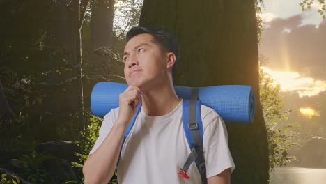 primer plano de un excursionista masculino asiático con una mochila de montañismo pensando en algo y mirando a su alrededor y luego levantando el dedo índice mientras explora la naturaleza del bosque