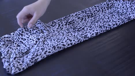 footage of a woman folding a t-shirt with a print