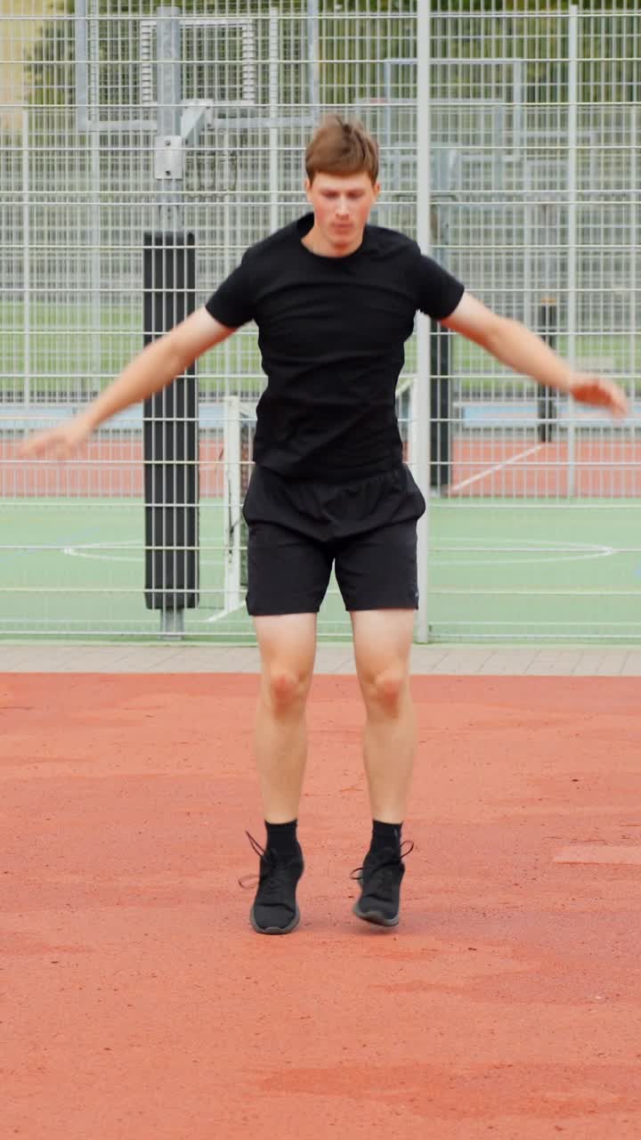 Young european man jumping jacks during an outdoor cardio workout, engaging in active physical burpee on a sports court, demonstrating fitness, health, and a dynamic lifestyle, static slow motion shot