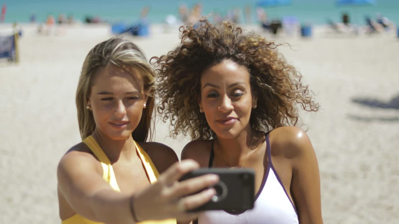 mujeres deportivas tomando selfie en la playa