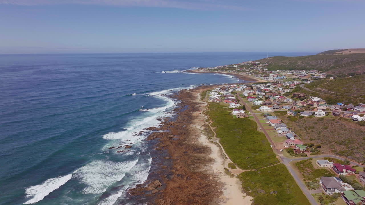 todavía bahía avión no tripulado cinematográfica playa pequeña ciudad de surf jardín ruta sur de áfrica jeffreys bahía casas y edificios olas chocando contra el arrecife tarde en la mañana tarde movimiento hacia adelante