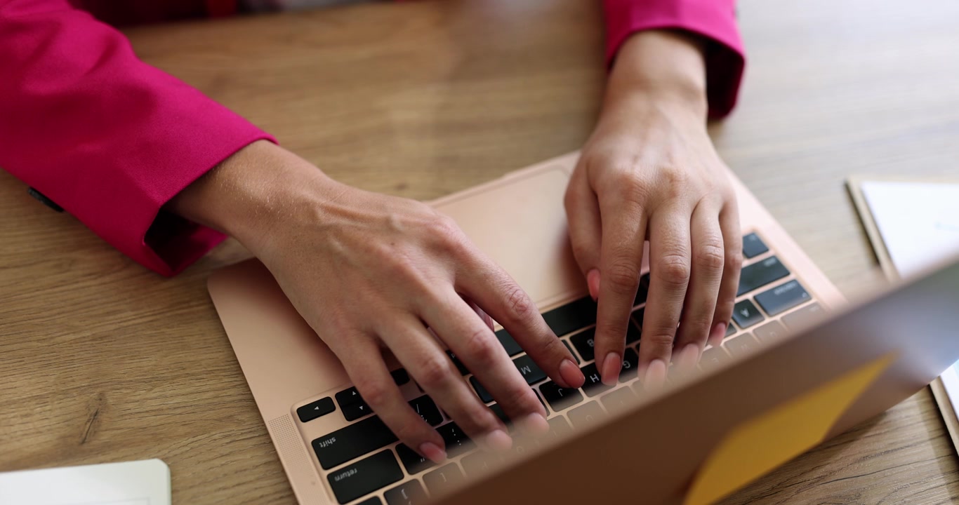 A young woman in the office opens a laptop on the table