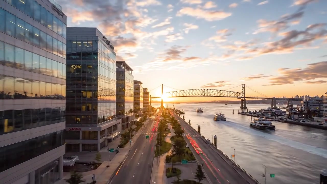 Paisagem Urbana Cénica ao Anoitecer: Luzes da Cidade Refletidas na Arquitetura Moderna com uma Orla Marítima Serena e uma Ponte Bonita Contra um Céu de Pôr do Sol Deslumbrante