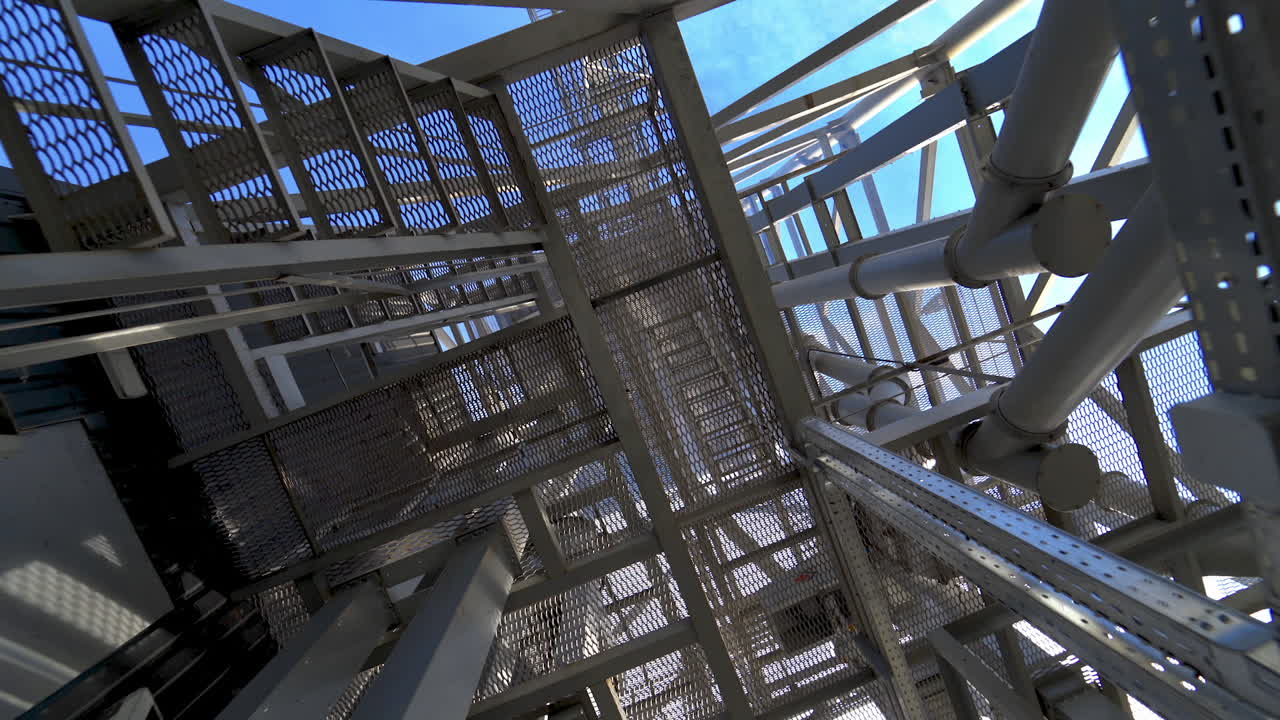 Steel frame construction on a factory. Modern storehouse construction. Metal structures of stairs rising up. Industrial plant.