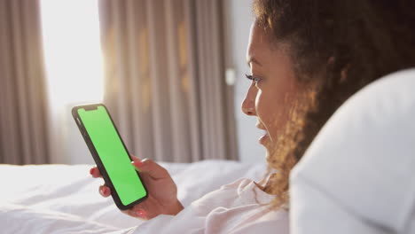 Woman-Sitting-Up-In-Bed-Looking-At-Mobile-Phone-After-Having-Woken-Up