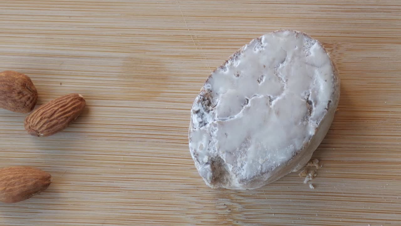 Panning view of almonds, mantecado and butter on a wooden table.