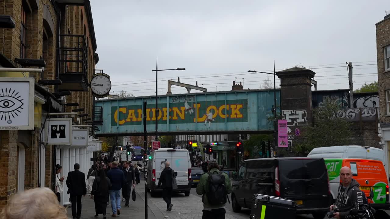 Iconic Camden Lock sign with tourists and bustling street scene at Camden Market on a cloudy day