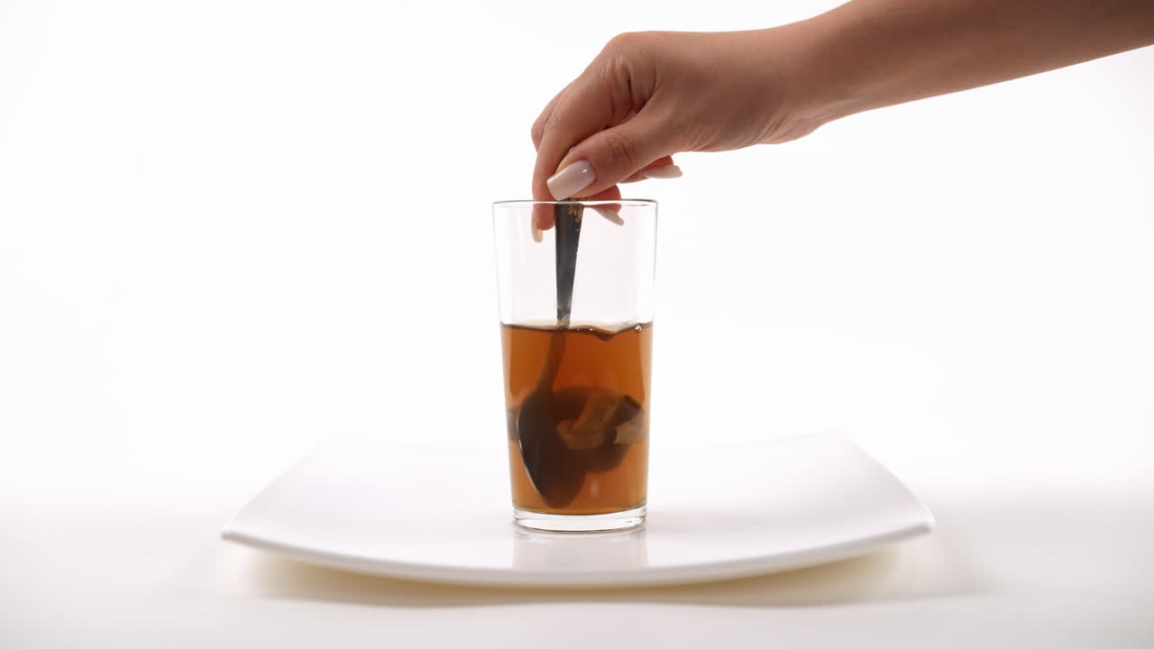 색 접시 위 에 있는 유리 컵 에 차 가방 을 넣고 따뜻 한 호박 김 을 넣는 것