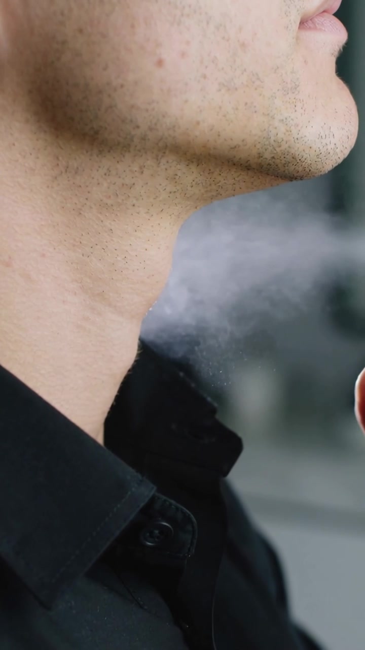 Video verticale: Premendo l'erogatore, uomo in camicia nera che spruzza profumo sul collo al lavandino, bottiglia di vetro