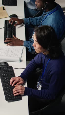 Vertical video Call center coworkers in diverse office helping customers