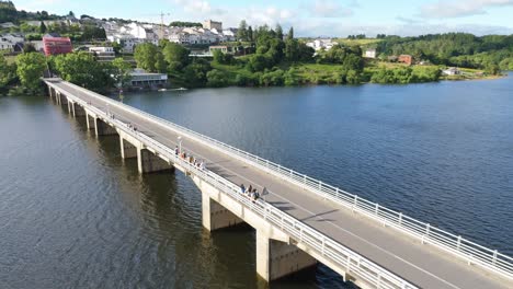 aerial descending view of portomarín through new portomarin bridge over minho river, lugo