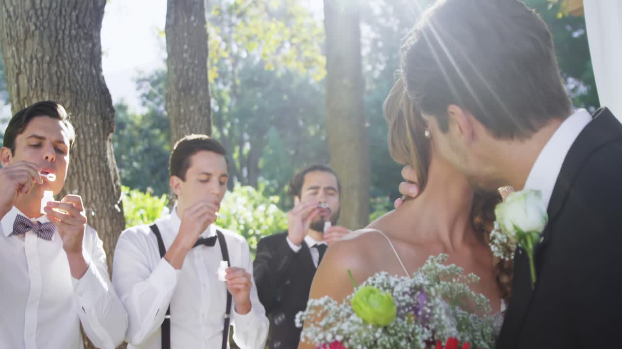 신랑과 신부가 배경에서 서로 키스하고 손님이 거품을 불어 4k 4k