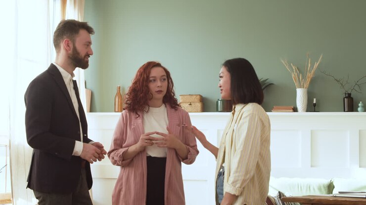 Three Multicultural Colleagues Having A Conversation Standing In The Living Room 2