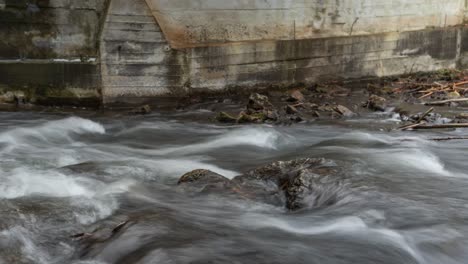 Zeitraffer-Der-Flussströmung,-Die-über-Felsen-Entlang-Der-Betonstaumauer-Fließt