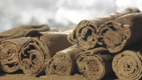 Slow-motion-shot-of-Cinnamon-stick-falls-on-top-of-Cinnamon-Sticks-pile,-Macro-shot