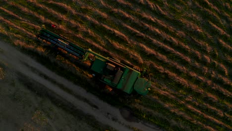 agriculture-machine-standing-in-field,-people-walking-around-and-cleaning-it,-making-dust-clouds,-camera-is-rising-up