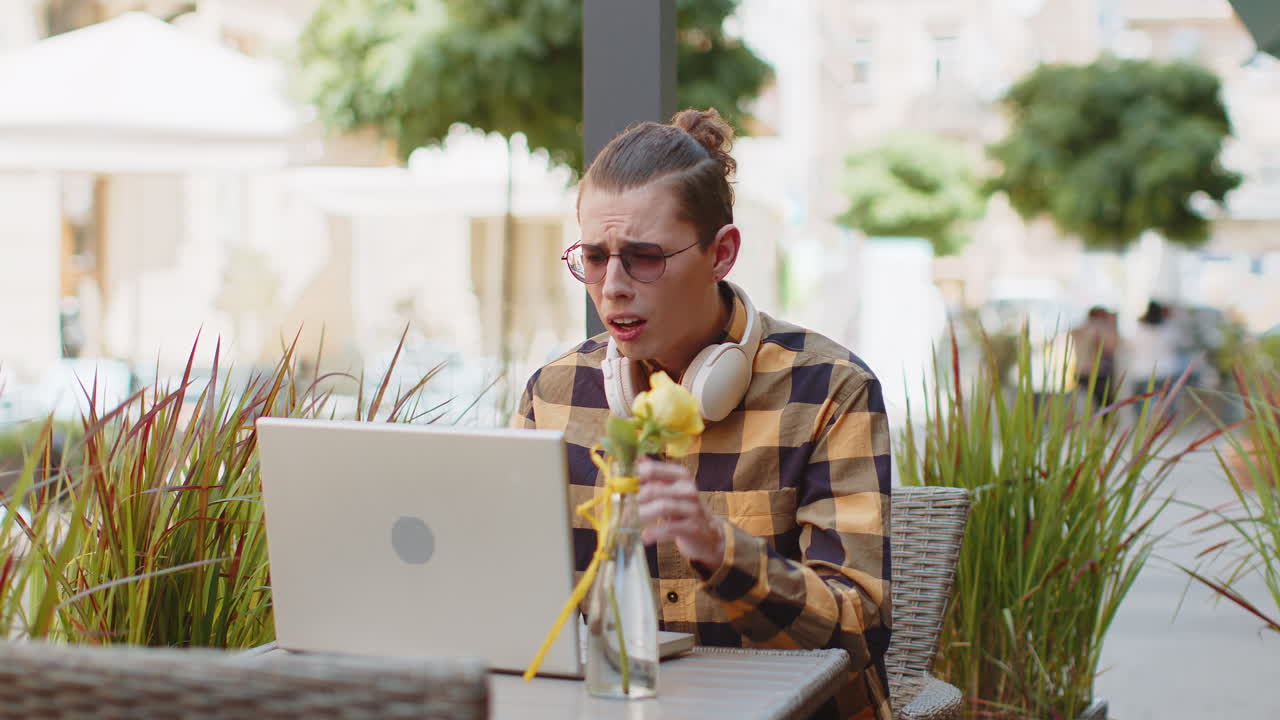 Sad unhappy man tourist using laptop receive bad news game fail loss in urban city cafe terrace