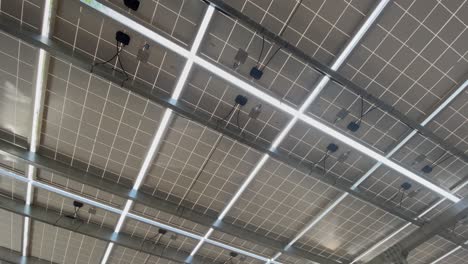 Gimbal-upward-view-shot-of-solar-panels,-sunlight-shining-through-panels