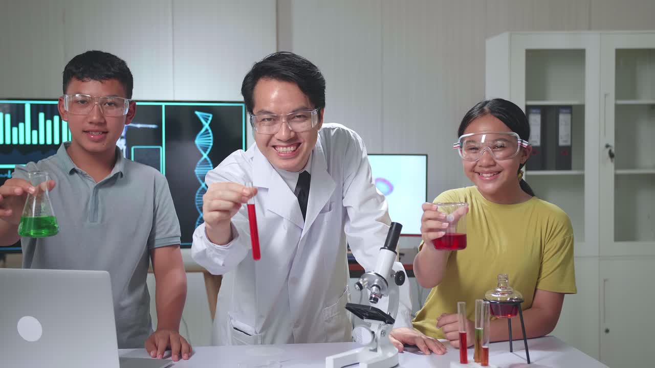 Young Asian Boy, Girl And Teacher Smiling While Holding Test Tubes In Classroom. Study With Scientific Equipment