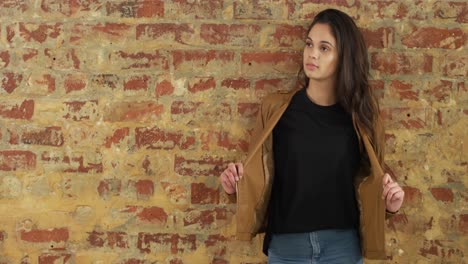 mujer caucásica mostrando su atuendo en una pared de ladrillo