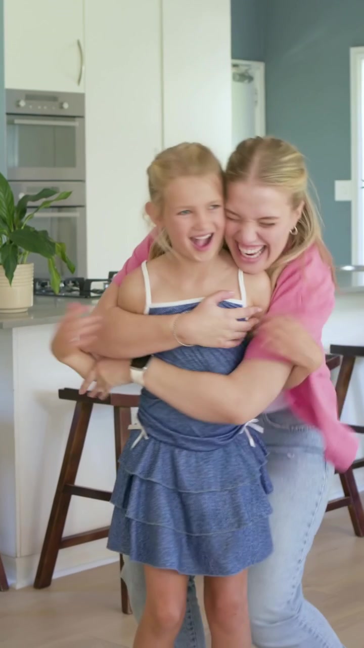 Vídeo vertical: Levantando as mãos, mãe guiando criança girando na cozinha, brincando, com o vestido esvoaçante