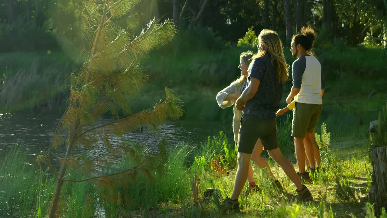 vista lateral de amigos divirtiéndose cerca del lago 4k