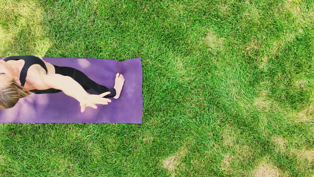 Watch the mindful grace and powerful poses of this healthy muscular woman performing yoga poses in a park