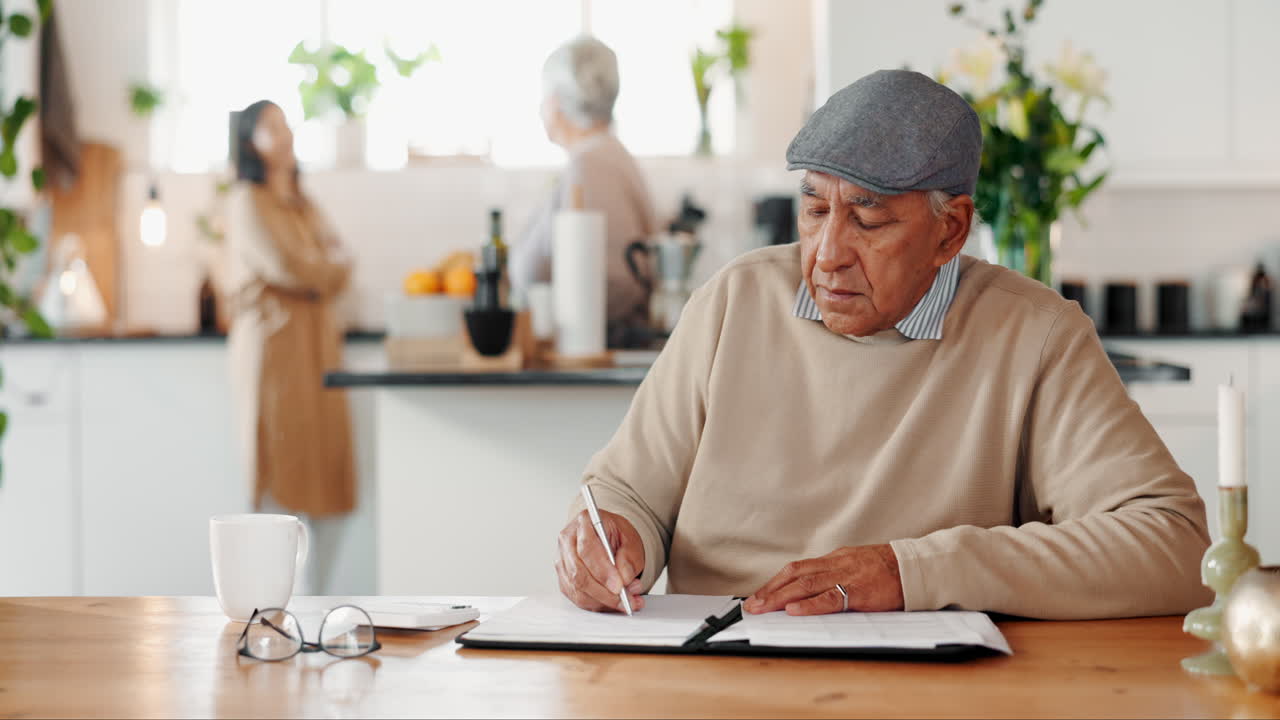 un hombre mayor escribiendo en un bloc de notas en la mesa de la cocina