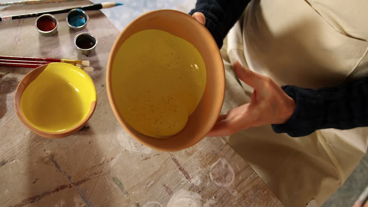 Male potter mixing watercolor in bowl at pottery workshop