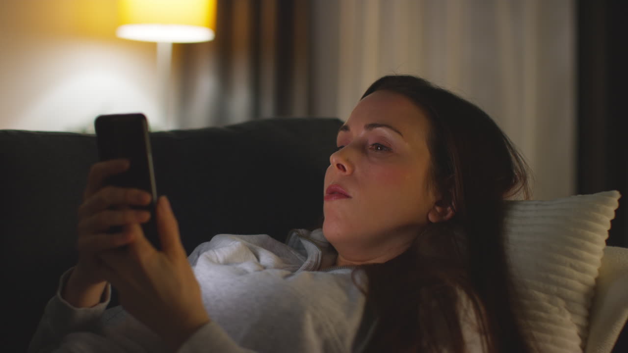 Close Up Of Woman Lying On Sofa At Home At Streaming Or Watching Movie Or Show Or Scrolling Internet On Mobile Phone 10