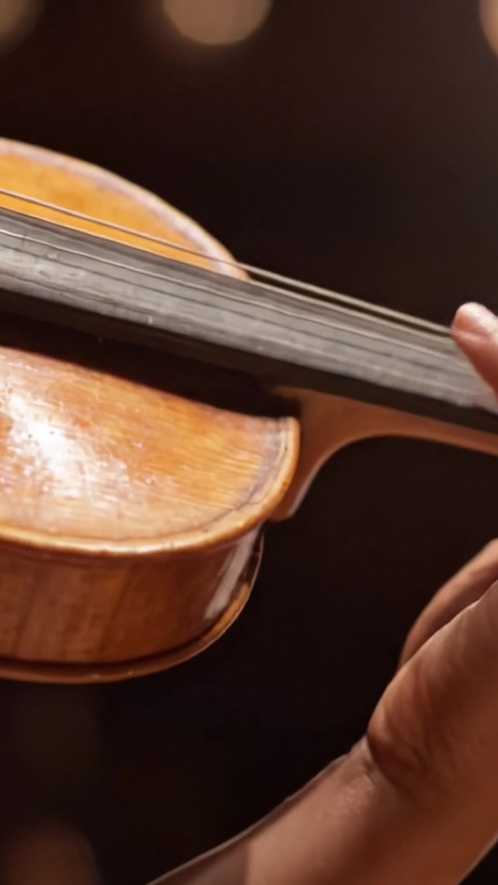 Un'esplorazione ravvicinata della tecnica del violino: cattura l'eleganza e l'abilità della mano di un esecutore mentre accarezza la tastiera dello strumento con illuminazione soffusa