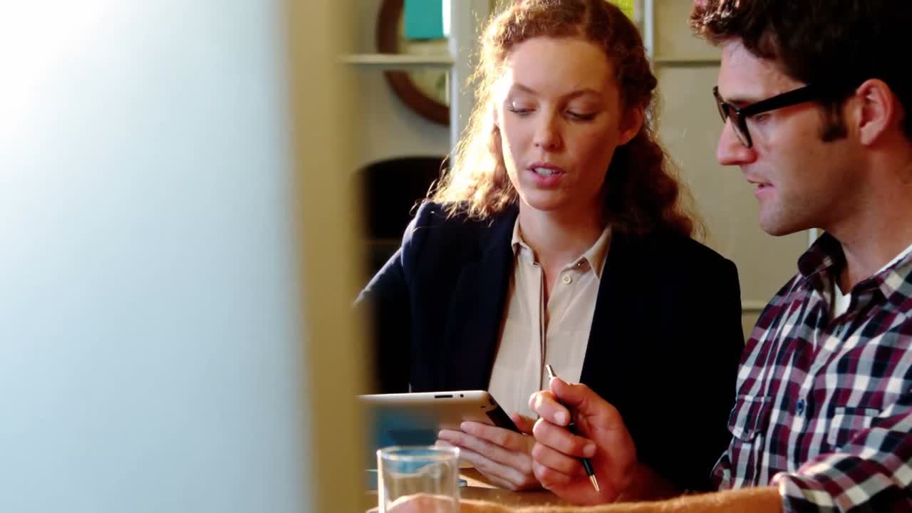 Male and female business executives using digital tablet