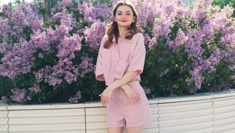 stylish woman in pink outfit amidst lilacs