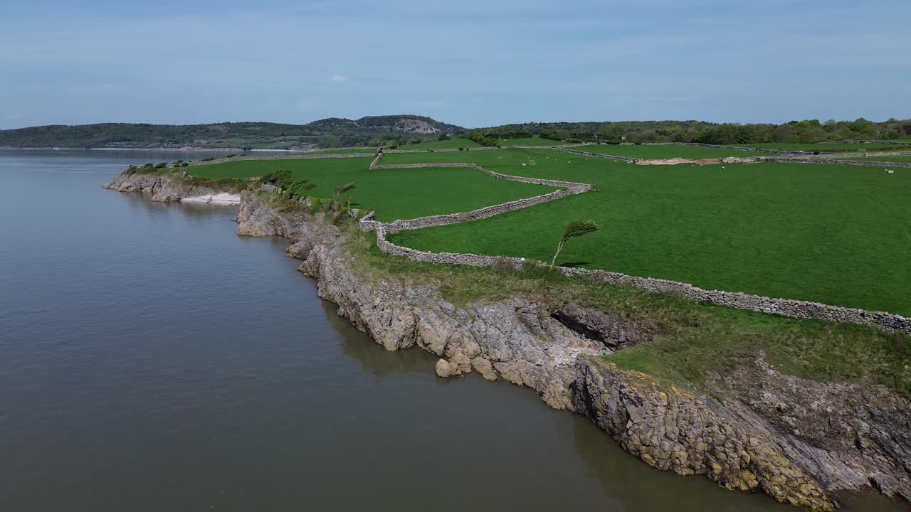 Lake district coastal farmland aerial view over stone wall boundary and mountain range horizon