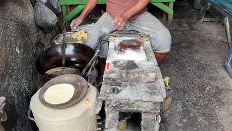 shot of an indian man making rotis on traditional indian stove at a roadside stall in kolkata, india