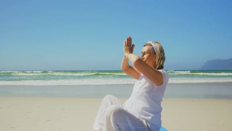 Side-view-of-active-senior-Caucasian-woman-performing-yoga-on-the-beach-4k