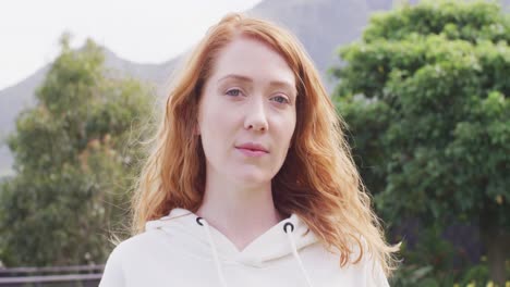 Video-portrait-of-happy-caucasian-woman-with-red-hair-smiling-to-camera-in-garden