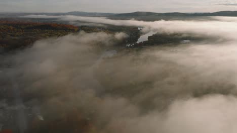 fly over cloud canopy over autumn forest and river in sherbrooke, quebec canada