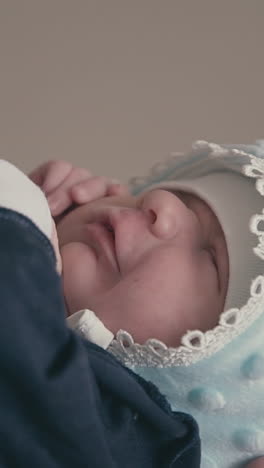happy young father in grey sweatshirt holds cute newborn son in tuxedo and warm hat at light wall extreme close view