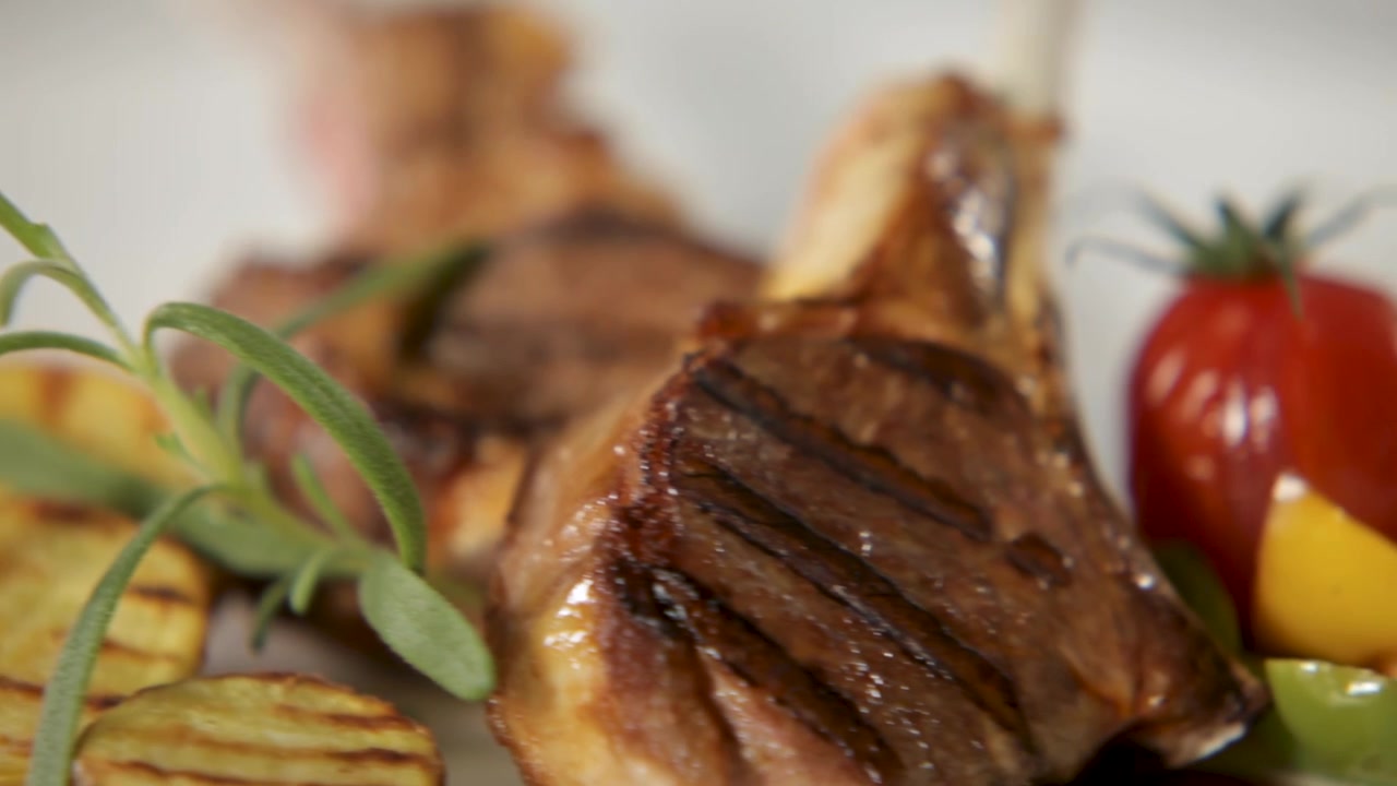 Grilled lamb chops served with roasted vegetables on a white plate