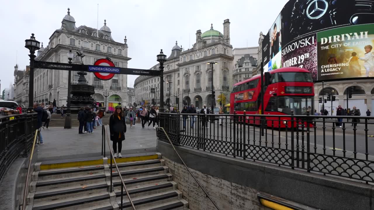 Piccadilly Circus with iconic red bus, LED ads, and a vlogger near the underground entrance