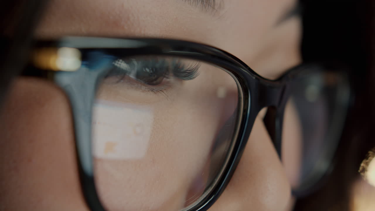 Close-up of woman wearing glasses, looking at a computer screen
