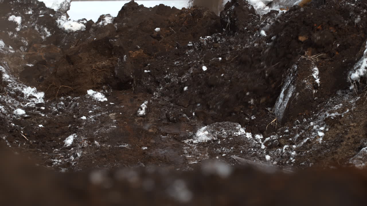 Macchinari pesanti che scaricano terreno e neve in uno scavo