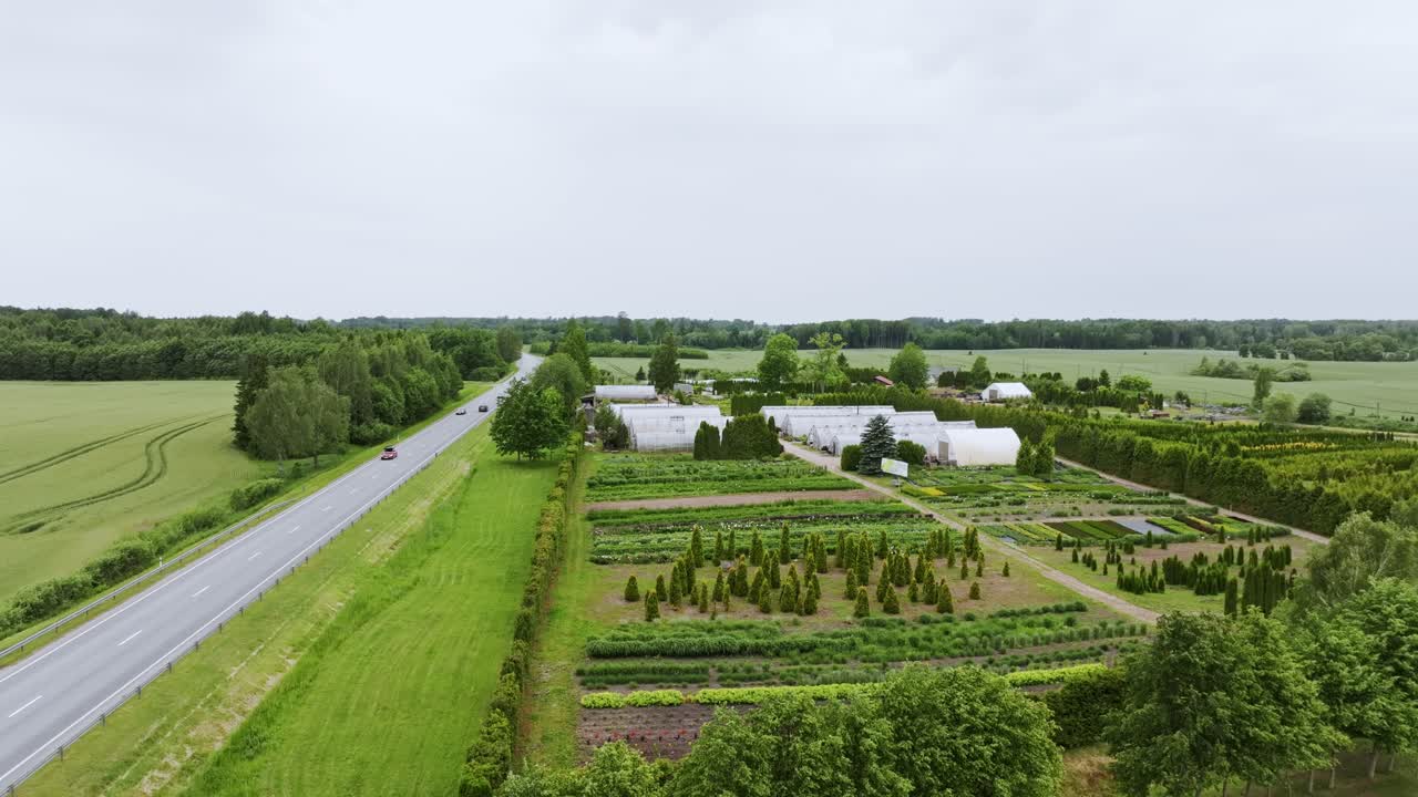 Overcast day with nursery field, greenhouses beside highway, Latvian countryside