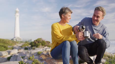 una pareja bebiendo café junto al mar.