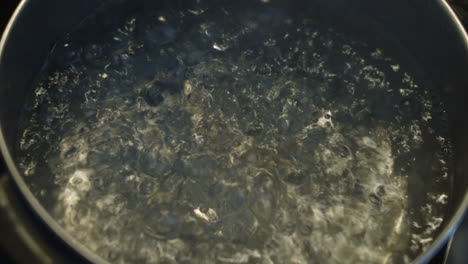 beautiful close up slow motion shot of a pot of boiling water on the stove with lots of boiling as bubbles form